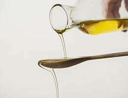 Olive oil pouring over a wooden spoon.