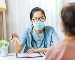 A masked provider talks to a patient.
