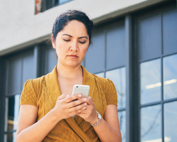 A woman with a worried expression checks her phone.