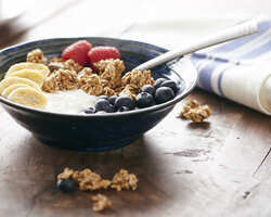 A bowl of granola with fruits and yogurt.
