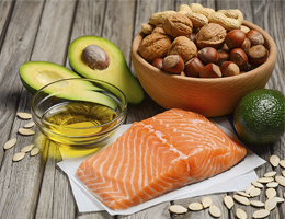Salmon, avocados, oil, nuts and seeds on a wooden table.