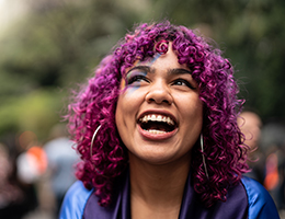 A smiling young woman with purple hair.