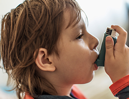 A young boy using an inhaler.